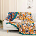 Colorful cotton throw blanket with bird and botanical patterns draped over a white sofa with decorative pillow in a bright living room