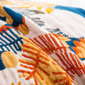 Close-up of soft cotton throw showing detailed terracotta, orange, yellow, and blue geometric and botanical weave pattern