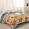 Cozy sunlit songbird cotton throw blanket with vibrant bird and leaf pattern draped over a bed in a bright, airy bedroom setting