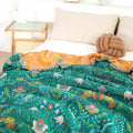 Reversible cotton blanket on bed with green floral botanical print