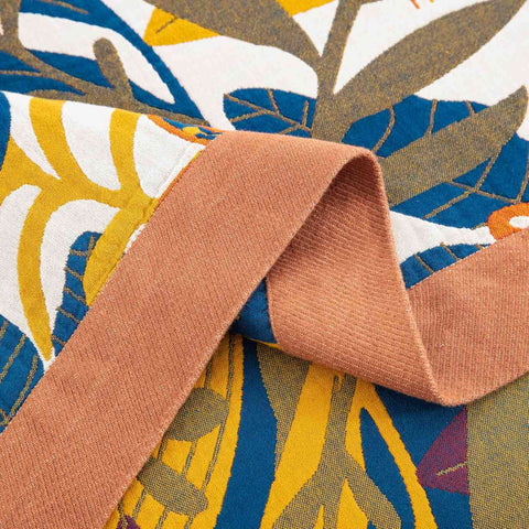Close-up of terracotta trim on cotton blanket showing textured fabric and vibrant geometric and floral patterns