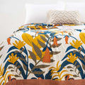 Close-up of Terracotta Fields Cotton Blanket showing vibrant floral and leaf pattern in mustard yellow, burnt orange, and blue tones