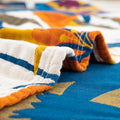 Detailed close-up of terracotta fields cotton blanket showing soft textured fabric and colorful stitched patterns