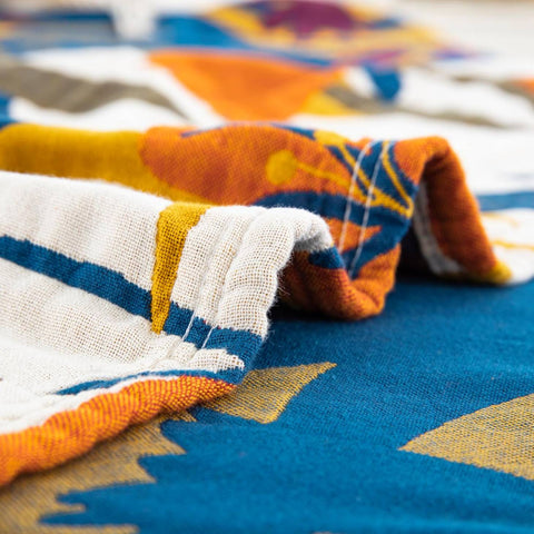 Detailed close-up of terracotta fields cotton blanket showing soft textured fabric and colorful stitched patterns