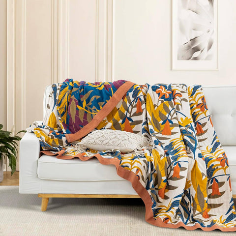 Terracotta Fields Cotton Blanket draped on white sofa showing bold geometric and floral pattern with warm terracotta trim