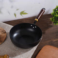  Traditional hammered iron wok with wooden handle on rustic table