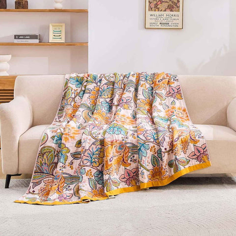 Autumn Garden Cotton Throw Blanket with warm floral patterns gracefully spread over a beige sofa in a sunlit living room