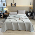 Light blue cotton quilt neatly laid out on minimalist bed