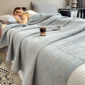 Woman peacefully sleeping under light blue cotton muslin quilt