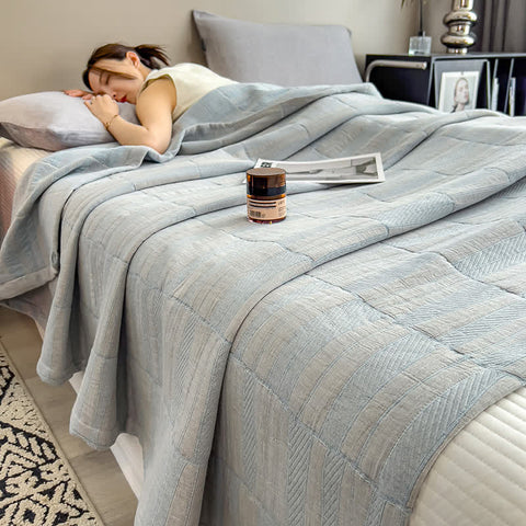 Woman peacefully sleeping under light blue cotton muslin quilt