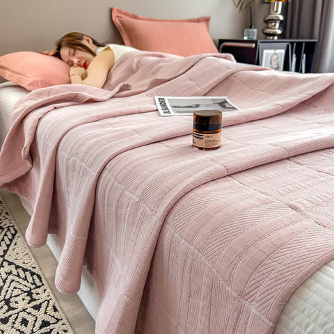 Soft pink quilt on bed with coral pillow and sleeping woman