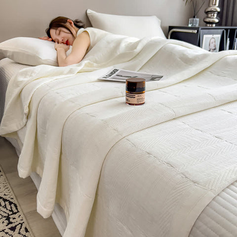 White minimalist cotton muslin quilt on bed with candle