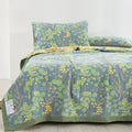 Verdant Bloom cotton quilt set on bed with matching pillowcases in green and yellow botanical print