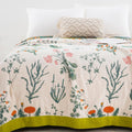 Verdant Bloom cotton throw blanket spread on bed with floral pattern and green border