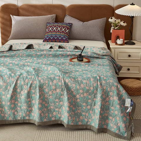 Reversible cotton summer quilt on bed with green vine leaf print