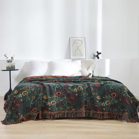 Vintage boho cotton throw blanket with floral pattern draped on a bed in a bright, minimalist bedroom setting with white pillows and soft natural light