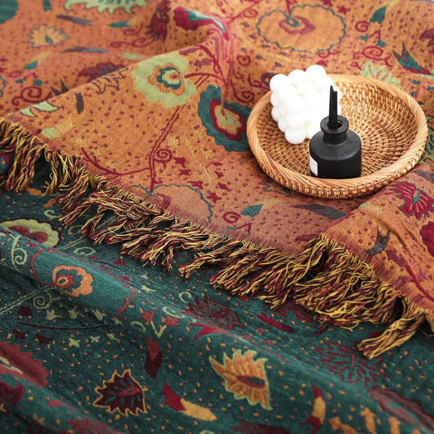 Close-up of vintage boho cotton throw blanket showing intricate floral patterns, fringed edges, and a decorative candle in a wicker tray