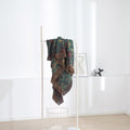 Vintage Boho cotton throw blanket hanging on white rack in minimalist room