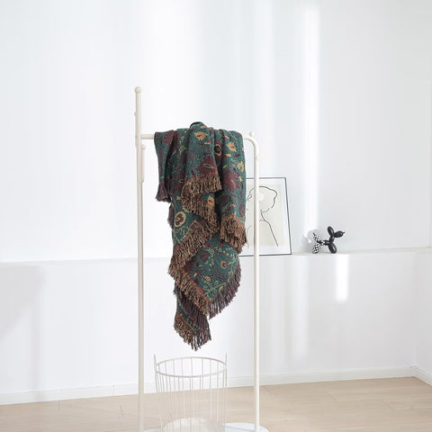 Vintage Boho cotton throw blanket hanging on white rack in minimalist room