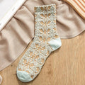 Vintage-style embroidered sock in cream with beige floral 3D lace design, laid flat on neutral fabric background.