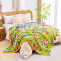 Vintage Garden Cotton Throw Blanket with vibrant floral patterns draped over a beige bed in a cozy, sunlit room with plant