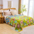 Vintage Garden Cotton Throw Blanket with vibrant floral patterns draped over a beige bed in a cozy, sunlit room