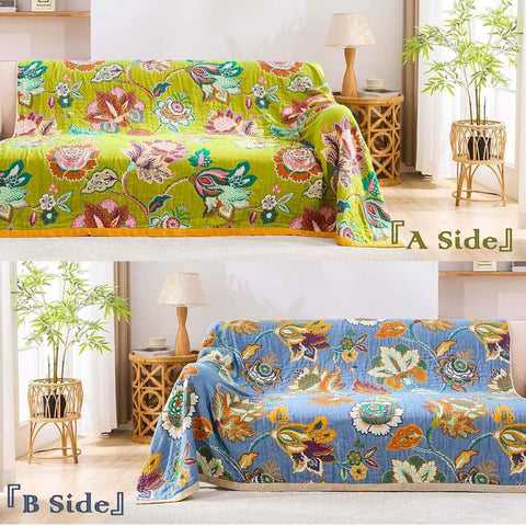 Vintage Garden Cotton Throw  Blanket reversible side showing warm floral patterns on beige and rich blue backgrounds, draped over a cozy sofa in a sunlit living room