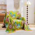 Vintage Garden Cotton Throw Blanket with warm floral patterns draped over a beige armchair in a cozy, bright living room setting