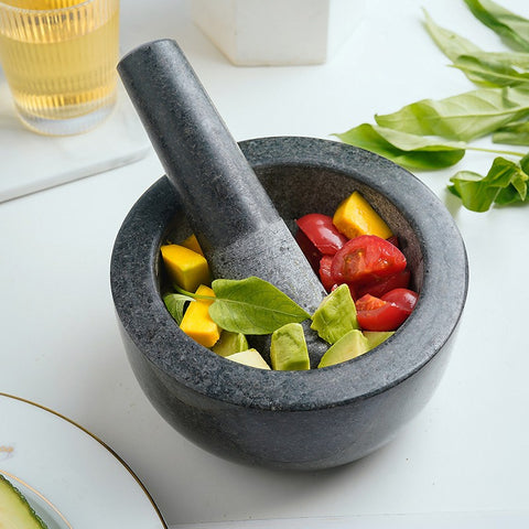 Vintage marble mortar filled with fresh vegetables and pestle on white kitchen counter