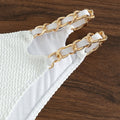 Close-up of double gold chain straps on white high-waisted bikini bottom
