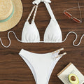Flat lay of Vita bikini with hat, glasses, and avocado on wooden surface