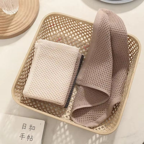 Beige and pink towels folded in a woven storage basket