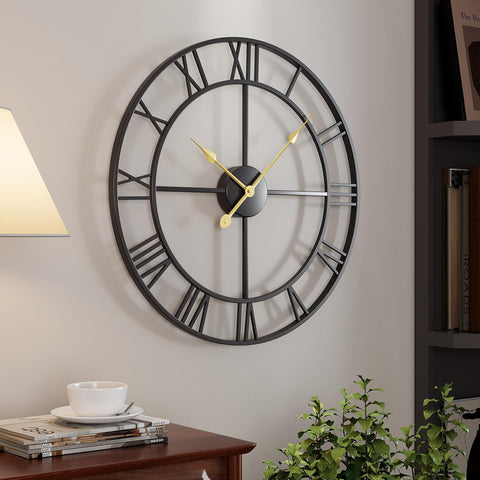 Large round wall clock with black frame and gold hands on a light gray wall.