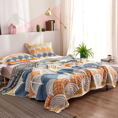 Vibrant warm orange and blue cotton blanket with scallop design draped on bed in cozy bedroom