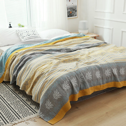 Yellow and gray rustic striped cotton gauze blanket laid out on modern bed