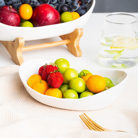 Person serving fruit from 3-tier bamboo fruit stand with ceramic bowls in modern kitchen