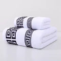 Two white towels with black geometric patterns on a light gray background