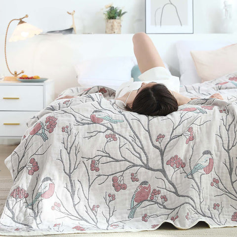 Woman lying under reversible bird print cotton throw