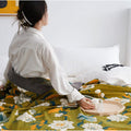 Woman holding scented candle on the wooden decorative plate under lightweight cotton floral quilt