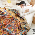  Woman sleeping under orange boho quilt with floral mandala design