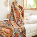 Woman wrapped in bold bohemian cotton quilt in bedroom